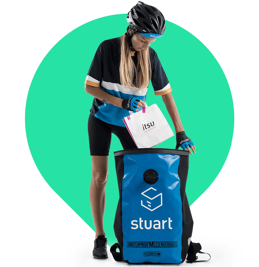 Female courier wearing Stuart uniform placing a food delivery bag labelled “itsu” into a large Stuart delivery backpack
